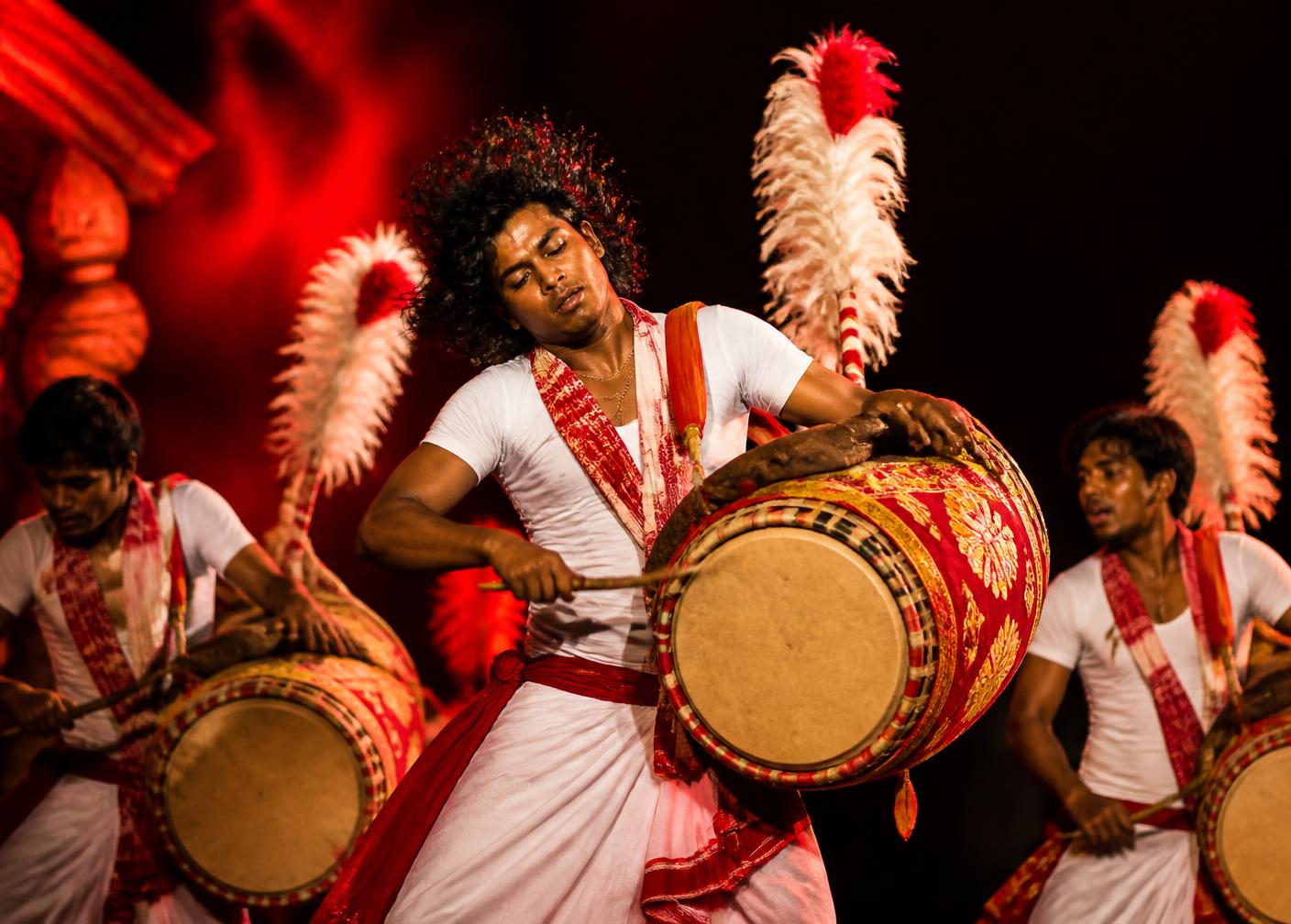 Bengali dhaki drummers performing under red festival light